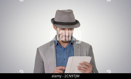Handsome smiling arab man in a hat walking and using tablet on g Stock Photo