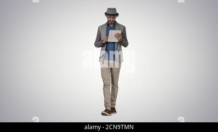Handsome smiling arab man in a hat walking and using tablet on g Stock Photo