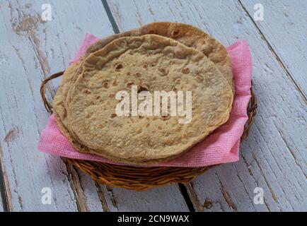 Indian flatbread chapatis served on a pink cloth and a wicker tray Stock Photo