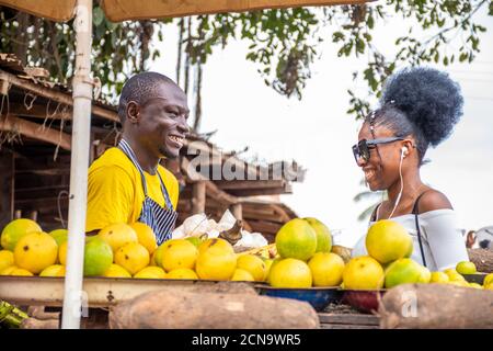 young african man selling in a market laughing with a customer Stock Photo