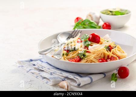 Spaghetti with pesto sauce, fresh basil and cherry-tomatoes. Stock Photo
