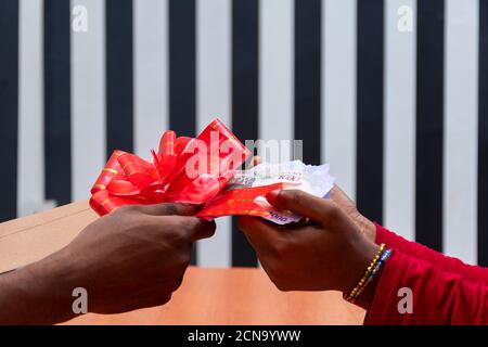someone giving a cash gift in an envelope wrapped with a ribbon Stock Photo