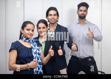 Portrait of confident Indian businesspeople raising their thumb as sign of victory, business deal, group of young entrepreneurs. Stock Photo