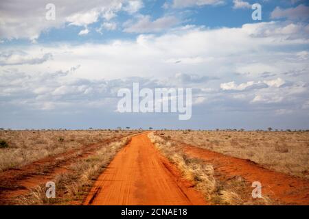 Red soil way, blue sky with clouds, scenery of Kenya Stock Photo