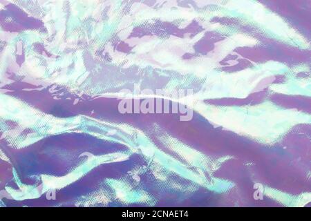 Holographic bright rainbow multicolor real crumpled texture background in light blue - purple toned. Stock Photo