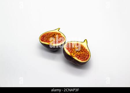 Two halves of figs isolated on a white background. View of ripe purple violet figs. The fig from inside against white background. Stock Photo