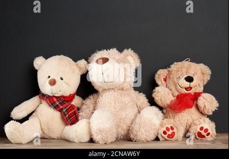 brown teddy bear sits on a brown wooden table, behind an empty black chalk board Stock Photo