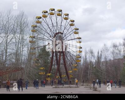 Pripyat, Ukraine, March 14, 2020. Tourists near the famous Ferris wheel in an abandoned amusement park in Pripyat. Cloudy weather, the sky is covered Stock Photo