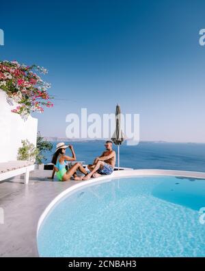 Santorini Greece, young couple on luxury vacation at the Island of Santorini watching sunrise by the blue dome church and whitew Stock Photo