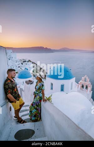 Santorini Greece, young couple on luxury vacation at the Island of Santorini watching sunrise by the blue dome church and whitew Stock Photo