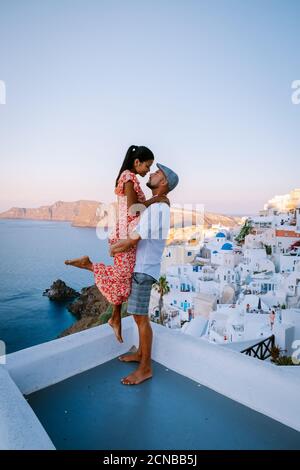 Santorini Greece, young couple on luxury vacation at the Island of Santorini watching sunrise by the blue dome church and whitew Stock Photo