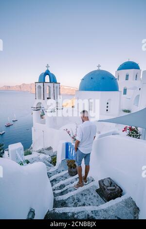 Sunset at the Island Of Santorini Greece, beautiful whitewashed village Oia with church and windmill during sunset, young men on Stock Photo