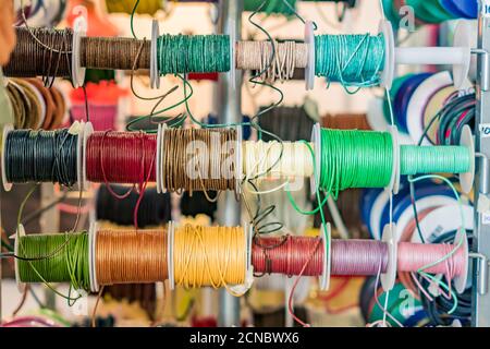 Set of spools with leather rope of different colors for sewing or crafting on  market Stock Photo