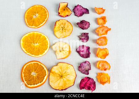 Healthy food organic nutrition. Sliced and dried apple, orange, carrot and beetroot in a row on textile background. Stock Photo