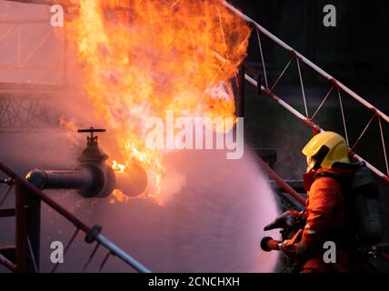 Firefighters using water fog spraying down fire from oil rig factory explosion Stock Photo
