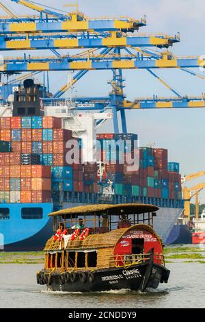 Tourist boat near container ship and cranes at Vallarpadam Container Terminal, a major Indian port, Kochi (Cochin), Kerala, India, Asia Stock Photo