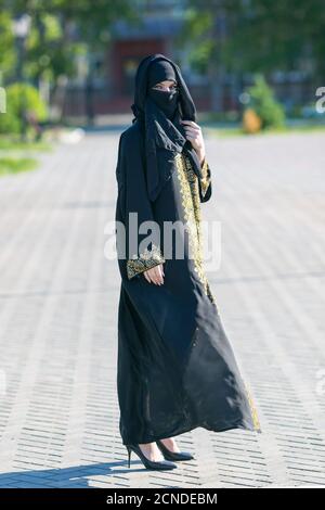 Oriental girl festive national dress in a European city Muslim woman in full growth, urban lifestyle. Stock Photo