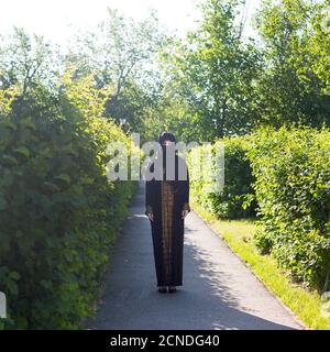 Muslim woman in full growth, urban lifestyle. Oriental girl in festive national dress in a European city Stock Photo