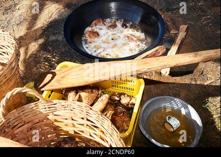 Close-up of pork meat frying in hot oil in a wok frying pan on a traditional fire place in a philippine home, called dirty kitchen Stock Photo