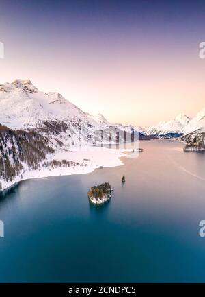 Aerial by drone of Lake Sils surrounded by snowy peaks during a winter sunrise, Engadine, canton of Graubunden, Switzerland, Europe Stock Photo