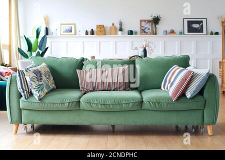 Large green upholstered sofa with pillows in the living room Stock Photo