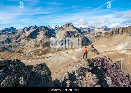 Rear view of man on top of Piz Nair looking towards Piz Suvretta mountain peak, Engadine, canton of Graubunden, Switzerland, Europe Stock Photo