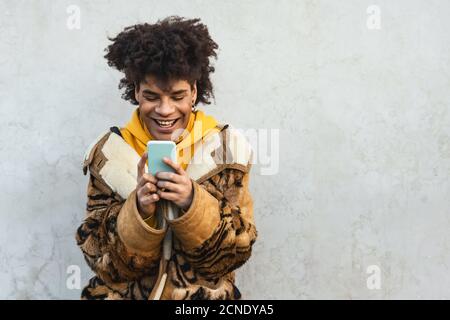 Happy Afro man using mobile smartphone outdoor - Young guy having fun with new technology app for smart device Stock Photo