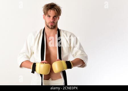 Handsome young muscular sportsman with golden boxing gloves isolated on white. Guy poses in white kimono Stock Photo