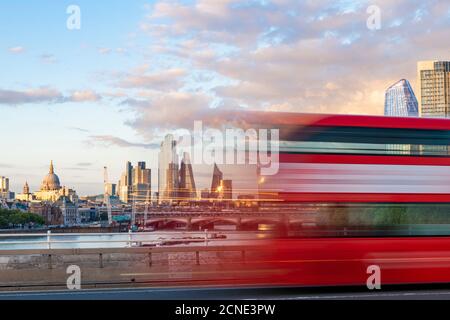 A red London bus goes past in a blur across Waterloo Bridge with the City of London and Southbank in distance, London, England, United Kingdom, Europe