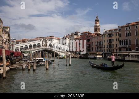 Gondolier with tourists in gondola approaching the Rialto bridge on the Grand canal in Venice,Italy, Europe. Stock Photo