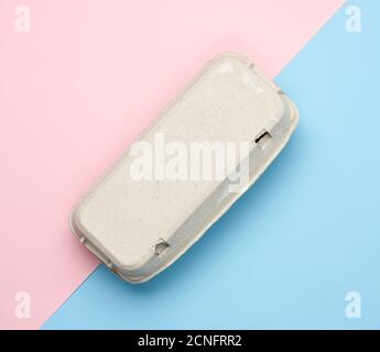 closed paper rectangular tray for chicken eggs on pink blue background, top view Stock Photo