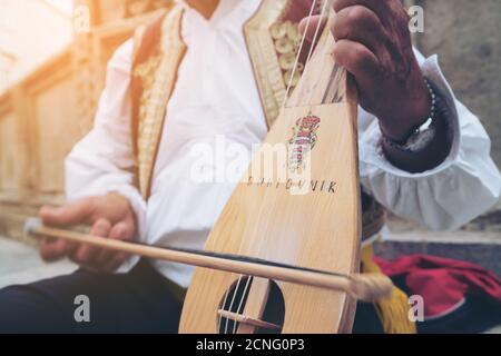 A busker plays traditional Croatian folk music with a 3-string instrument (lijerica) in the old city of Dubrovnik, Croatia. Stock Photo