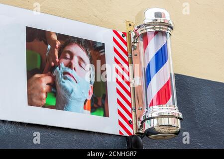 Traditional red, white and blue barber's sign pole outside a gents hairdresser's shop, Kilwinning, Scotland, UK Stock Photo