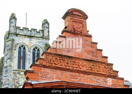 Top pediment of The Mother Lodge of Freemasonry, Masonic Lodge, Kilwinning, Ayrshire, Scotland, UK with Kilwinning Abbey tower in the background. Stock Photo