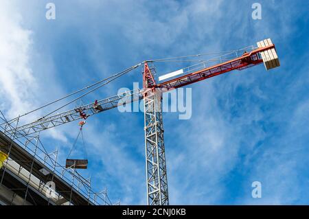 Red tower crane building against a blue sky with clouds. Building crane apartment Stock Photo