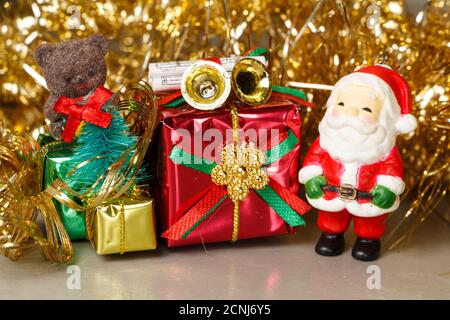 Santa Claus figurine with gift and golden tinsel as decoration for Christmas Stock Photo