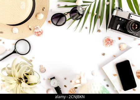 Traveler accessories on white background with retro camera, straw hat, sunglasses and tropical palm leaf. Essential vacation items, Travel concept Stock Photo