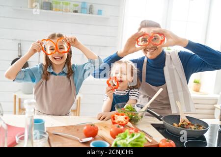 Healthy food at home. Happy family in the kitchen. Father and children daughters are preparing proper meal. Stock Photo
