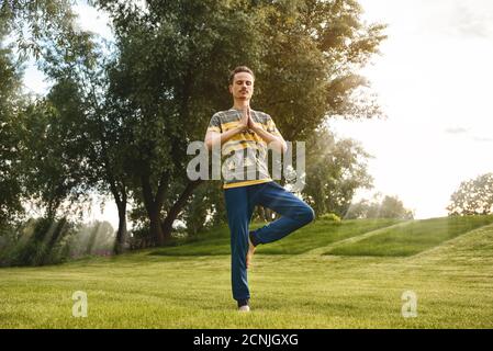 Fitness man doing exercise on one leg isolated in the park. enjoying nature, yoga and meditation concept. spiritual practices.ze Stock Photo