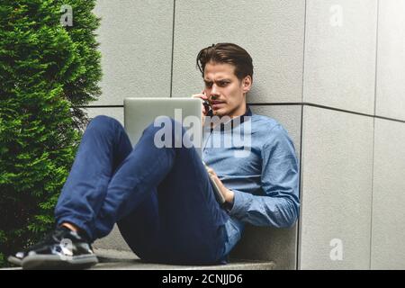 Pensive young caucasian man using laptop to chat online. Stock Photo