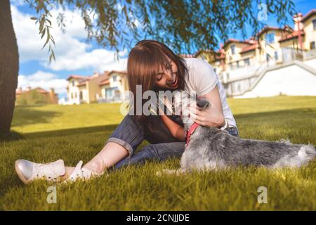 Caucasian joyful woman playing with her beloved dog in the park. The concept of love for animals. best friends. Dog breed Schnau Stock Photo