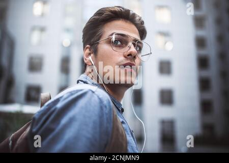Portrait of cheerful young handsome well dressed man with headphones thinking about new project. Stock Photo