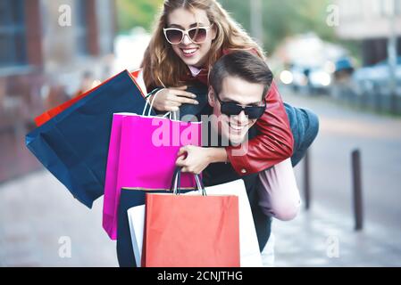 Couple in shopping together. Happy couple shopping together and having fun. Boyfriend carrying his girlfriend on the piggyback. Stock Photo