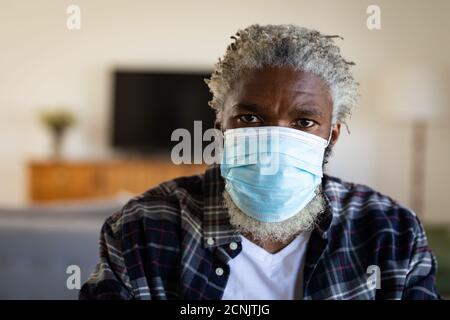 Portrait of an African American senior man sitting, wearing a face mask, social distancing and self isolation in quarantine lockdown Stock Photo
