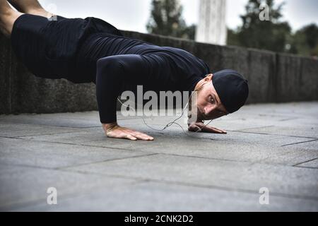 Healthy lifestyle concept. Muscular athlete exercising push up outside in city park. Stock Photo
