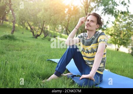 handsome stylish guy enjoys nature and dreams about something sitting in the park. peaceful sight Stock Photo