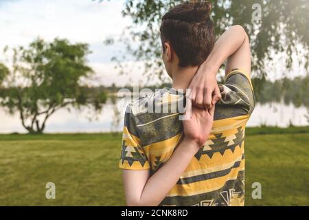 Man performing yoga young fitness man outdoor doing exercise. backview. puts his hands together behind his back Stock Photo