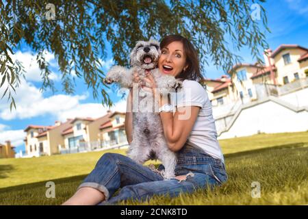 Caucasian joyful woman playing with her beloved dog in the park. The concept of love for animals. best friends. Dog breed Schnau Stock Photo