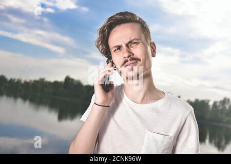 You will have problems man. Portrait of angry confused aggressive in bad mood guy irritably speaks on the phone on the backgroun Stock Photo