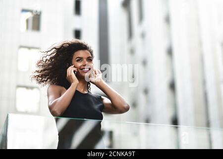 Pretty mixed race businesswoman speak by phone in city. Stock Photo